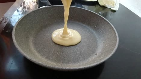 pouring some more dough on the frying pan to make a big pancake