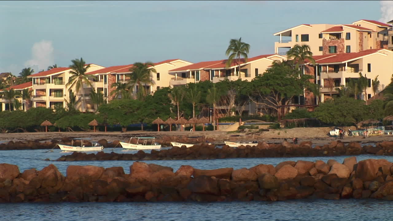 pequeñas olas se mueven a lo largo de la costa frente a botes de remos y casas frente al mar