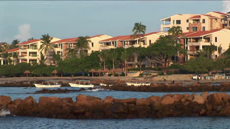 small waves move along the shoreline in front of rowboats and beachfront homes