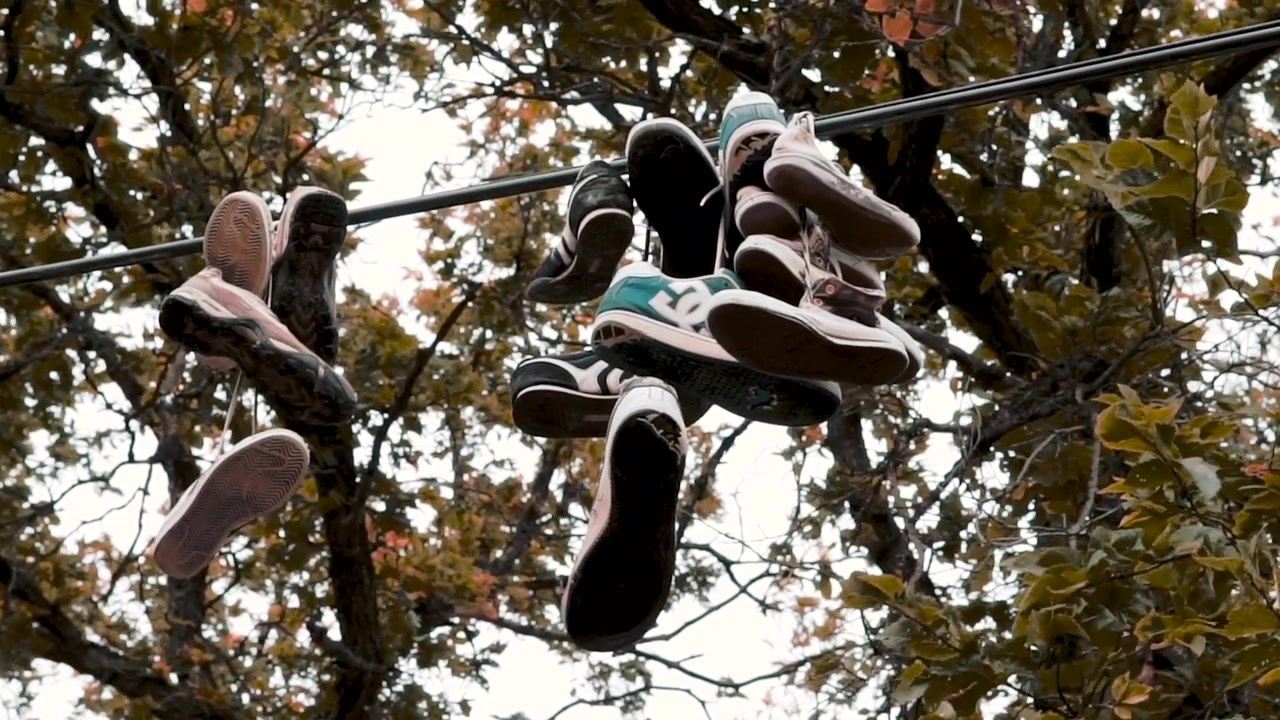Sapatos pendurados em um fio sobre uma estrada com árvores