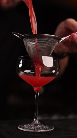 bartender pouring a red cocktail