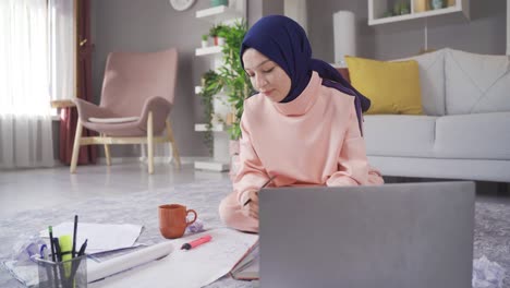 Female-muslim-student-studying-using-laptop-and-books.