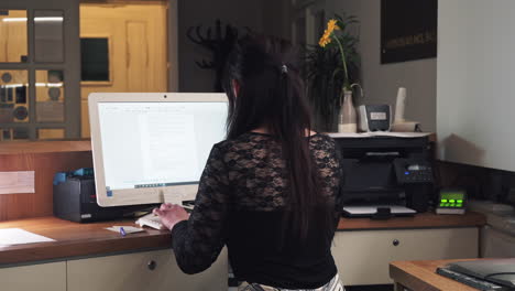 Girl-at-hotel-reception-using-computer,-writing-keyboard,-back-midle-shot-view