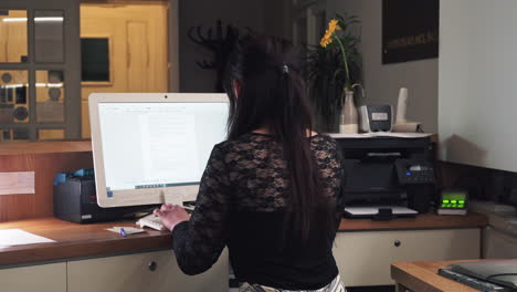 chica en la recepción del hotel usando computadora, escribiendo teclado, vista trasera de tiro medio