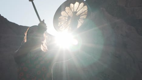 close up young caucasian woman playing tambourine in sunshine