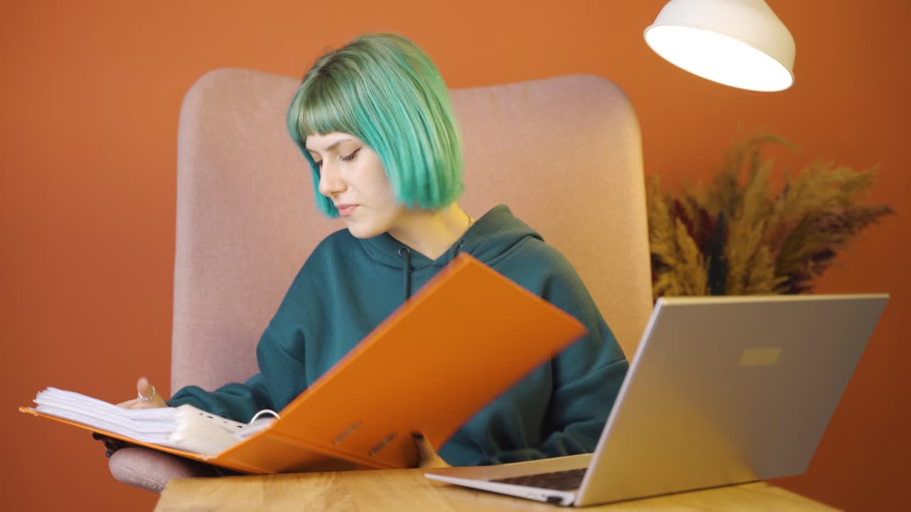 노트북에서 일하는 젊은 여성이 화를 내며 파일을 던집니다.