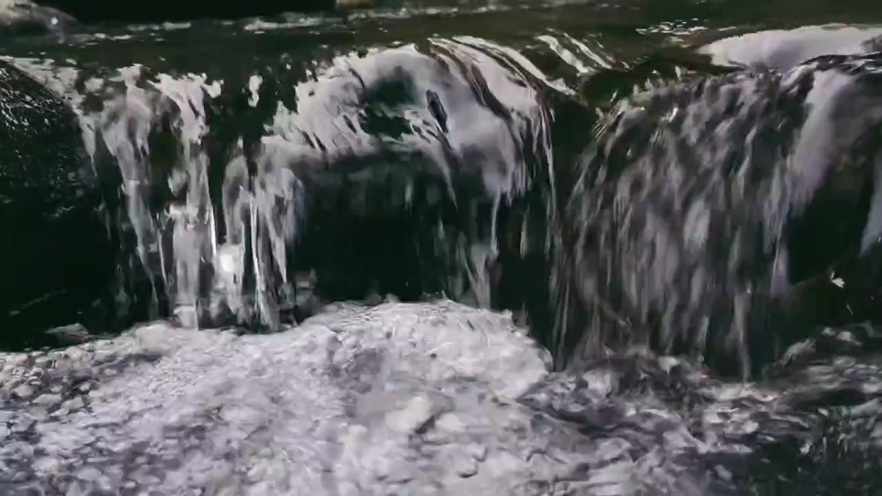 Acqua cristallina che scorre su rocce scure in un ruscello
