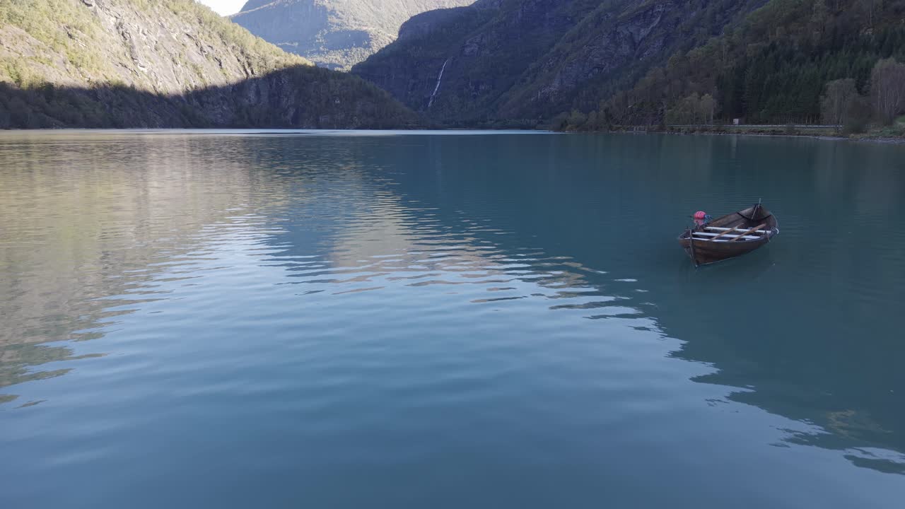 A lonely boat in turquoise green water of mountain lake in Norway. Drone footage