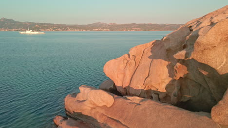 White-Van-Parked-Near-The-Seaside-Spot-Among-Beautiful-Rocks-At-Sunset-In-Sardinia,-Italy---Aerial-Drone-Shot