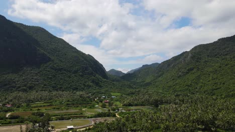 reverse aerial footage revealing mountains, coconut trees, saltpans, farms, and provincial houses