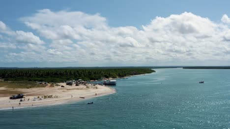 Dolly-in-aerial-drone-shot-approaching-the-beautiful-tropical-Restinga-beach-where-the-large-Curimataú-river-meets-the-sea-near-Barra-do-Cunhaú-in-Rio-Grande-do-Norte,-Brazil-on-a-summer-day