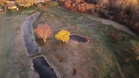 top-down drone shot of misty golf course early in the morning