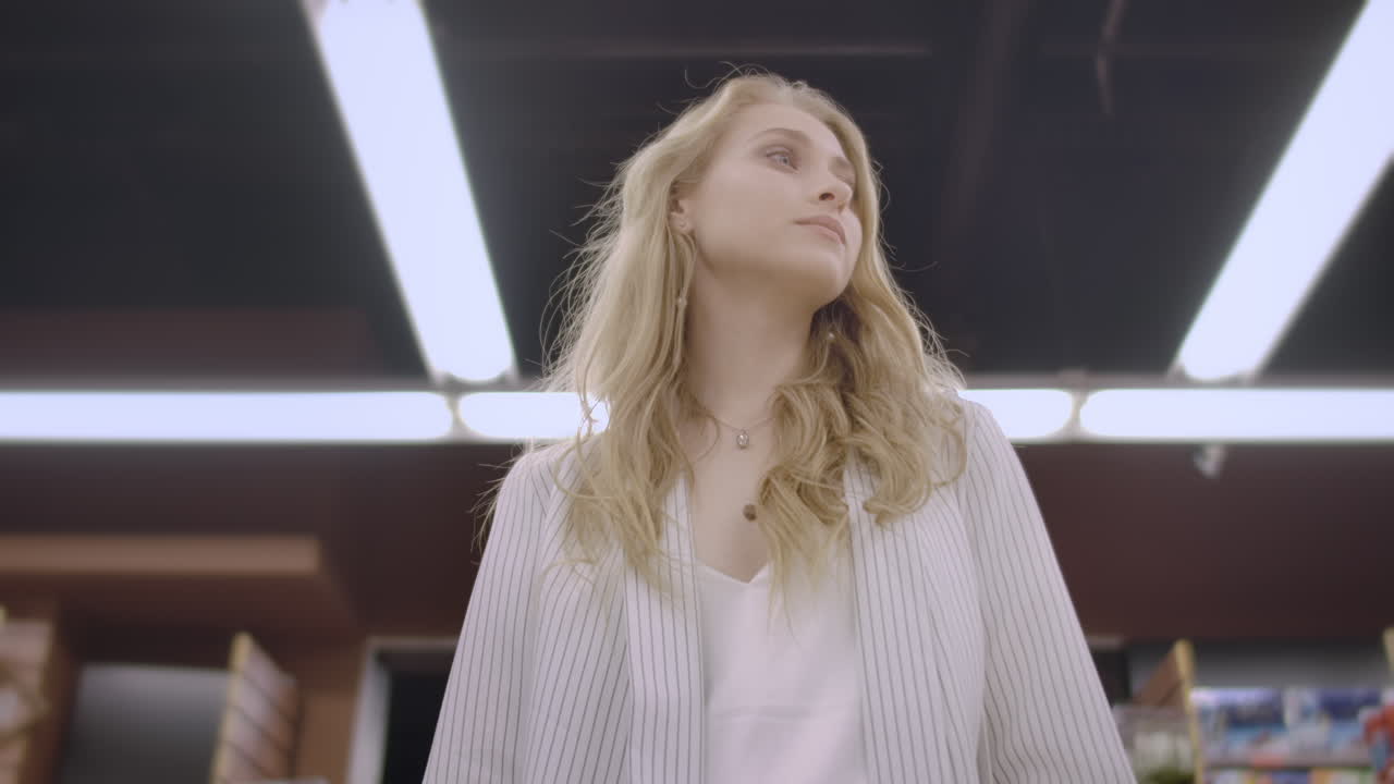 바구니를 가진 식료품 가게의 여성 구매자는 선반과 카운터 사이에 걸어 상품과 제품을보고 슈퍼마켓의 여성