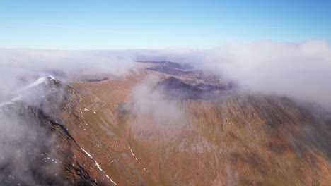 drone shot pulling backward through clouds above a mountain, helvellyn, lake district, cumbria, uk