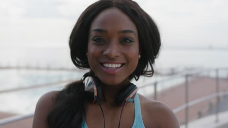 portrait of young african american woman laughing cheerful wearing headphones seaside swimming pool