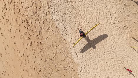 aerial view of a person with surfboard on a sandy beach