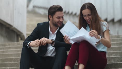 Businesswoman-and-businessman-looking-at-hight-graphs-on-papers-at-street