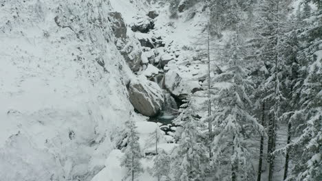 Aerial-reveal-of-small-waterfalls-in-snow-covered-wilderness