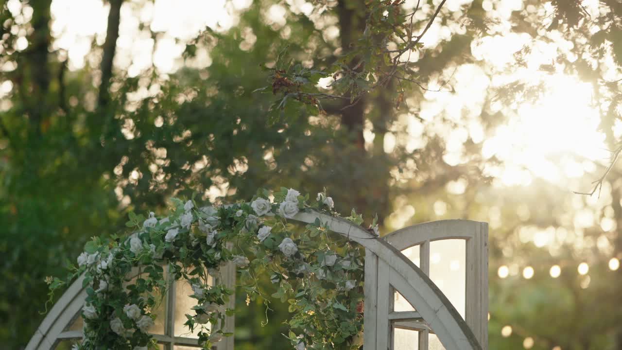 황금 시간 동안 빛이 비치는 야외 환경에서  장미와 함께 꽃 결혼 아치
