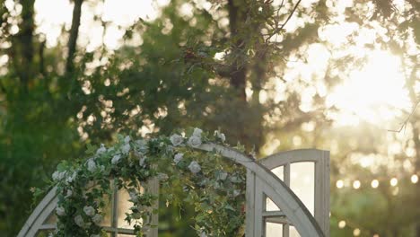 floral wedding arch with white roses in a sunlit outdoor setting during golden hour