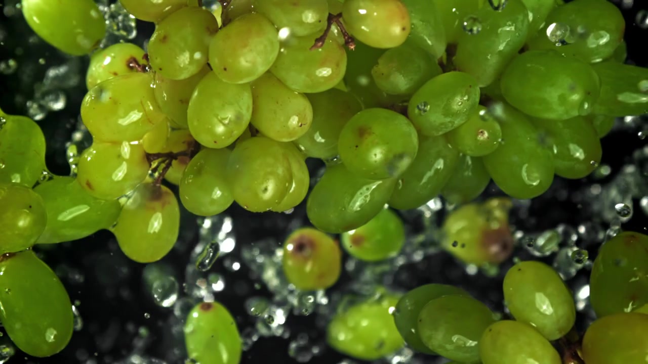 Uvas verdes frescas com água espirrando em fundo preto