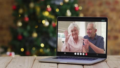 Caucasian-senior-couple-waving-on-video-call-on-laptop,-with-christmas-tree