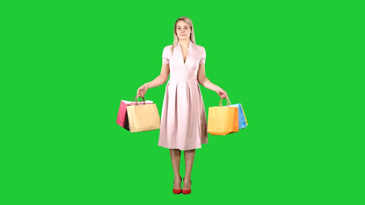 Woman with shopping bags in pink dress standing on a Green Screen, Chroma Key
