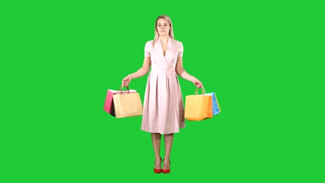 woman with shopping bags in pink dress standing on a green screen, chroma key