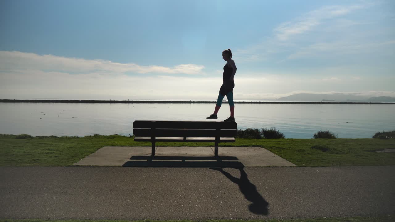 Young girl walks on park bench like a balance beam and dismounts