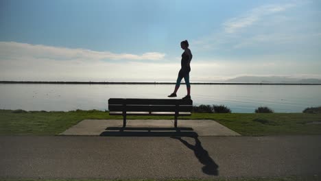 young girl walks on park bench like a balance beam and dismounts