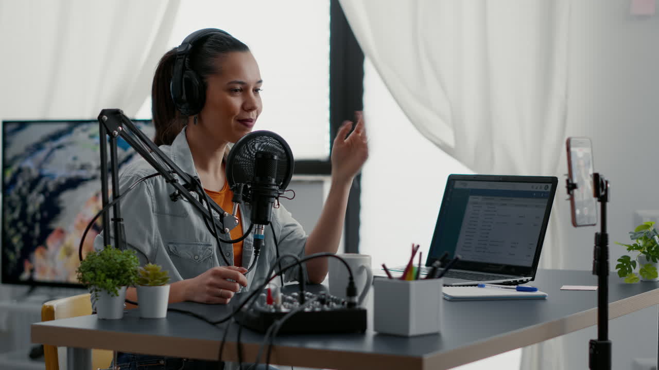 Internet live talk show host broadcasting with smartphone while tweaking sound on mixer