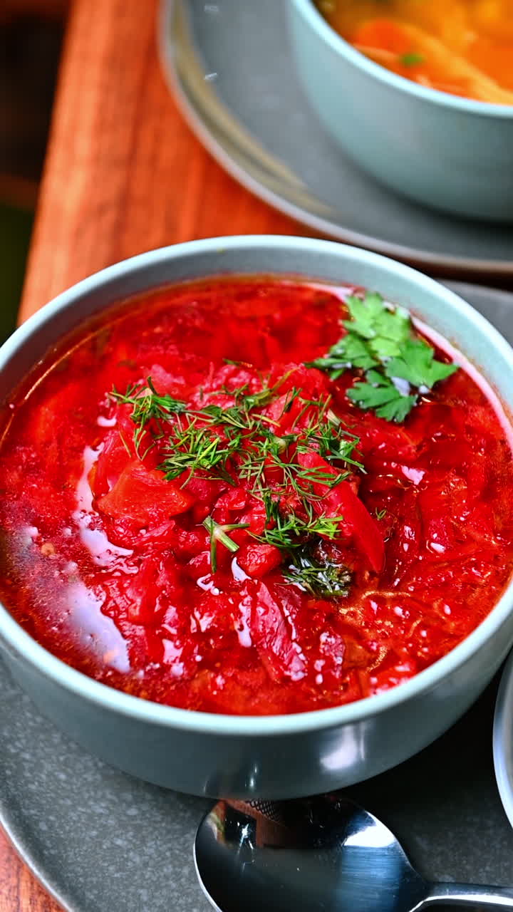 Close view of red soup bowl. Rich red soup topped with fresh herbs served in a ceramic bowl on a table