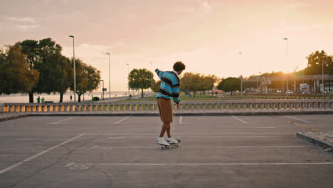 young man balancing skateboard at evening back view. guy riding skate vertically