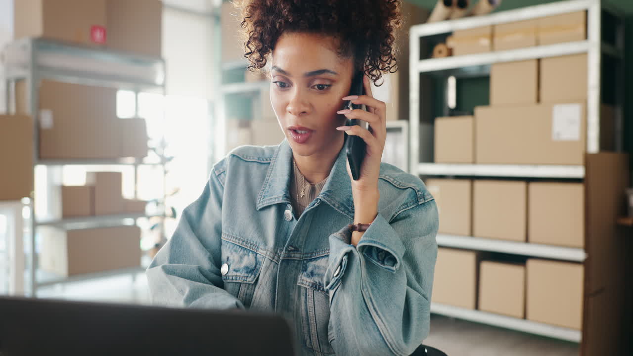 Woman on Phone Working on Laptop Surrounded by Boxes