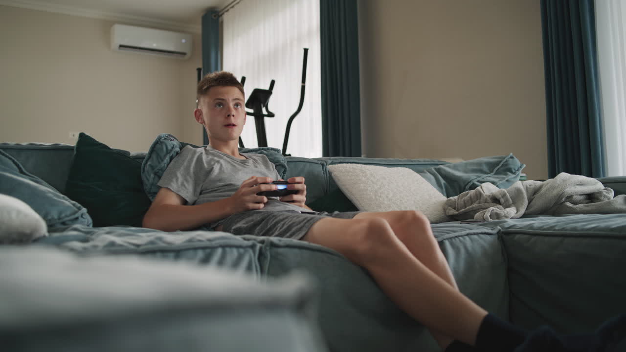 adolescente jugando videojuegos en un sofá