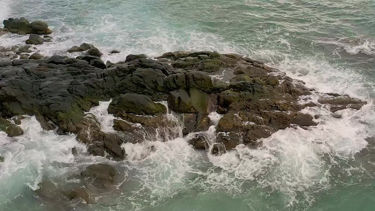 Riprese aeree cinematografiche al rallentatore di onde che si infrangono sulla costa rocciosa di Looc Beach a Surigao City, Filippine