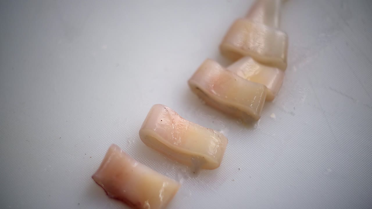 Close up view of a chef´s hand picking a slice of squid tube.