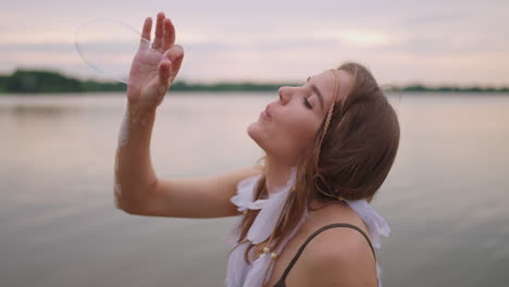 a young female artist shows a soap bubble show by blowing up large soap bubbles with her hands in slow motion