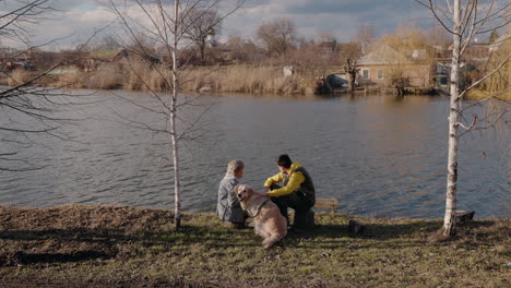 couple and dog relaxing by a river