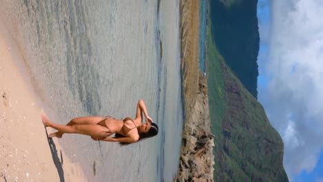 a stunning beach girl in a brown swimsuit tans and bathes in the ocean on a tropical rocky seashore