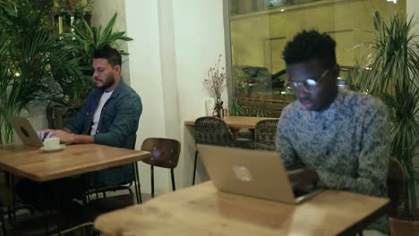 multiethnic men working with laptops in coffee shop