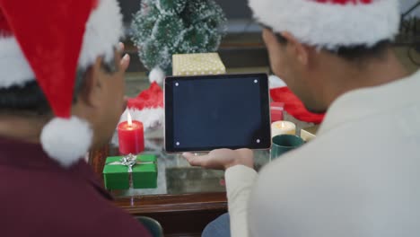 padre e hijo biracial haciendo una videollamada de navidad en una tableta con pantalla en blanco y espacio para copiar