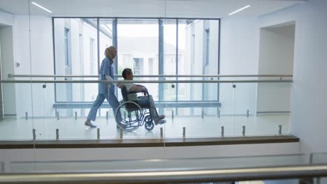joven médico empujando al paciente en silla de ruedas en el hospital 4k