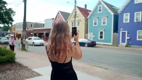 Woman-taking-photo-of-colourful-buildings-on-her-cell-phone-in-Halifax,-Nova-Scotia,-Canada