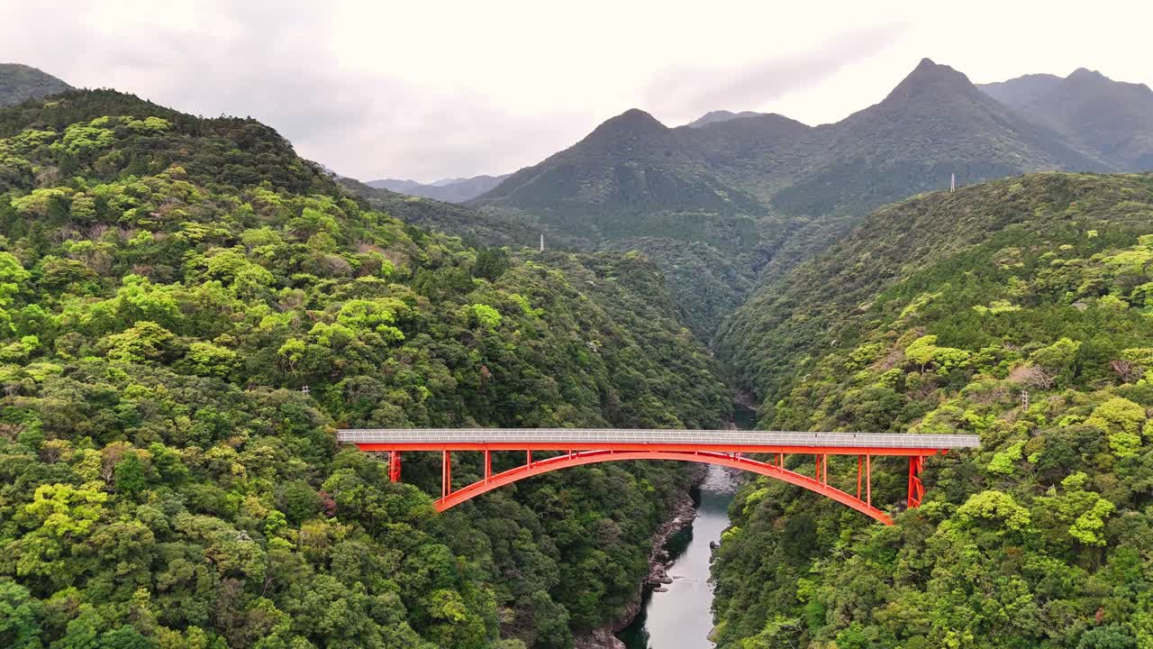 Red Bridge Spanning a River in a Lush Mountain Valley