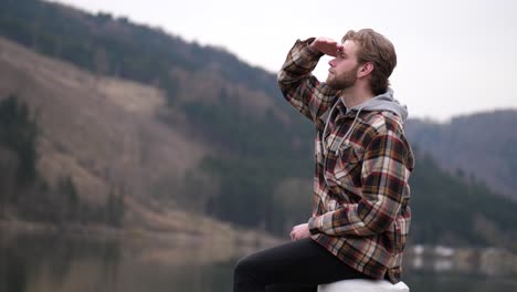 a blond young man throws a stone presumably into a water