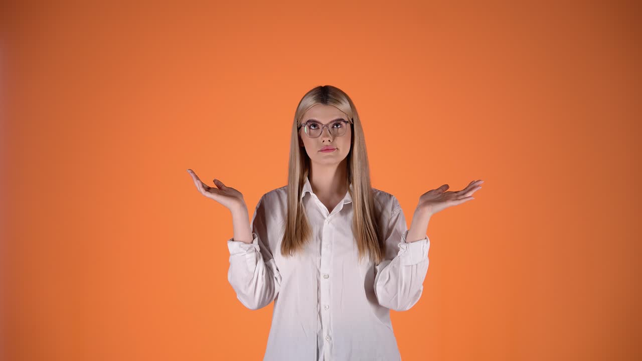 chica rubia insegura incierta y dudosa, encogiéndose de hombros y brazos manos gesto, colorido rodaje de estudio