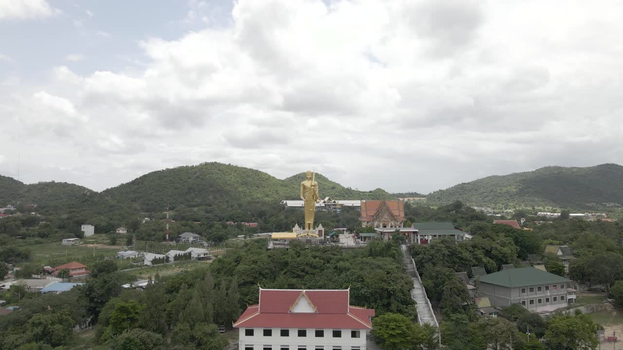drone volando hacia atrás desde la estatua dorada de buda en el templo wat khao noi, hua hin