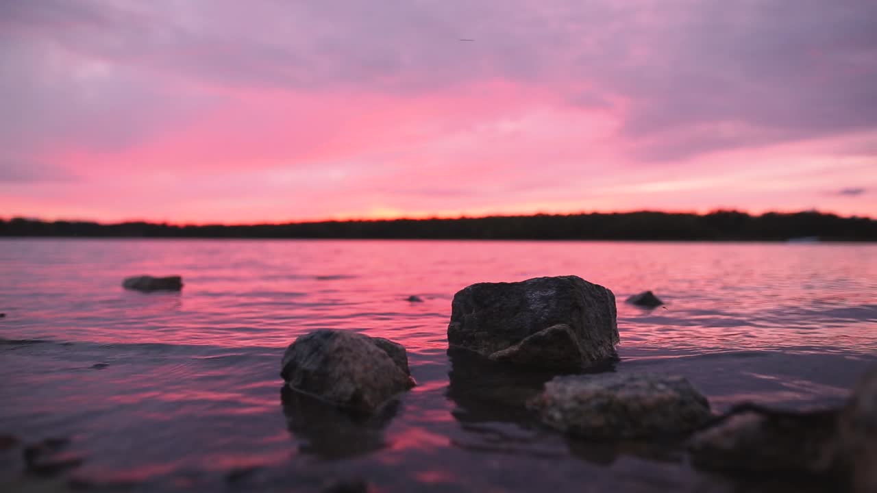 grandes rocas en el lago al atardecer naranja y rosa