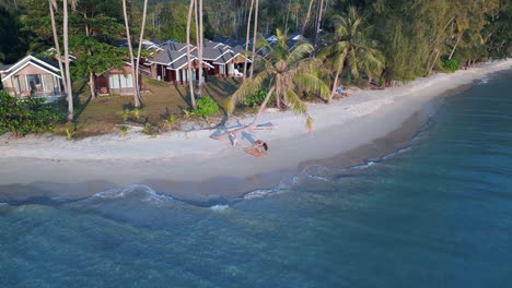 woman doing gymnastics exercise under coconut palm on dream beach